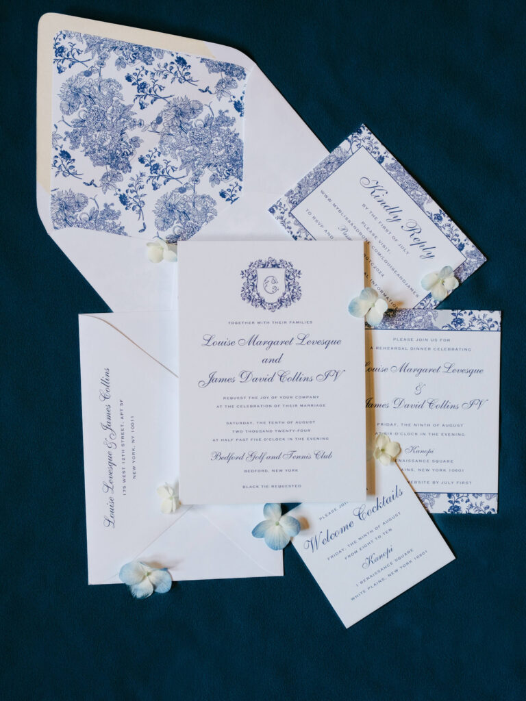 Flat lay of blue and white wedding invitation suite featuring floral envelope liner and calligraphy details for Louise and James’ New York country club wedding