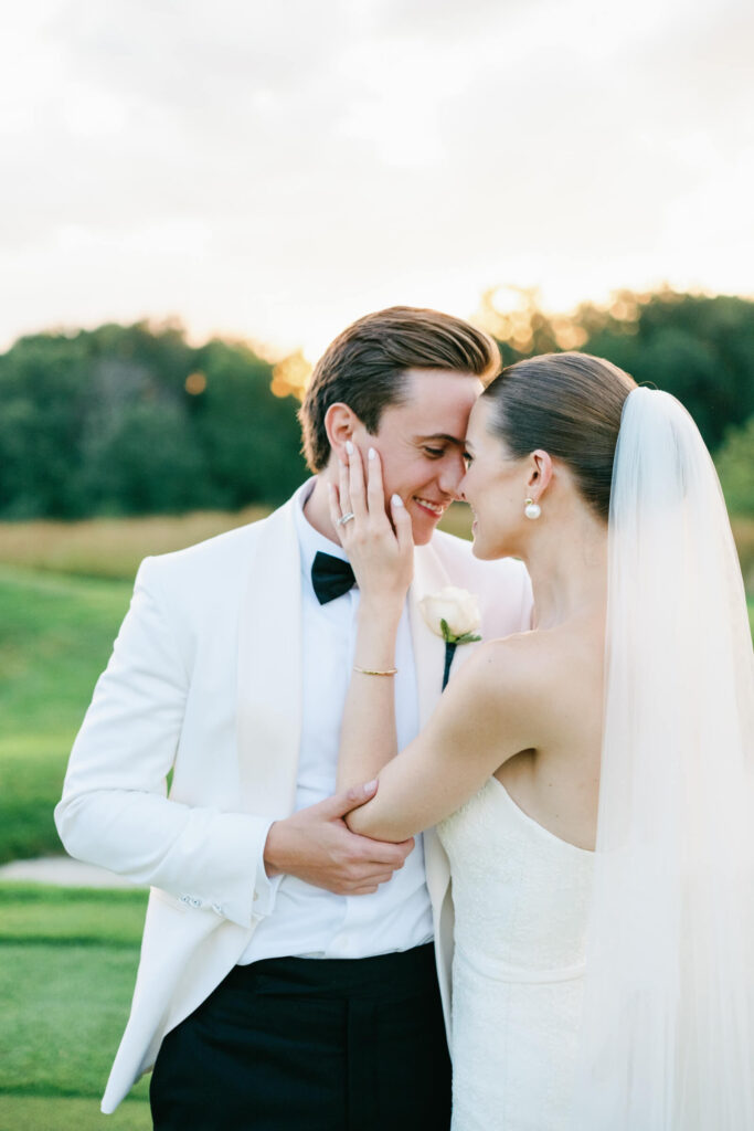Close-up of the bride and groom pressing their foreheads together, smiling tenderly at sunset.
