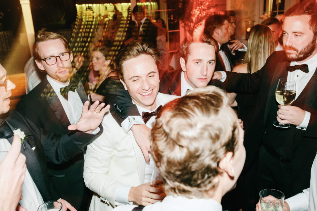 Groom celebrating on the dance floor with groomsmen, surrounded by motion blur and vibrant lighting