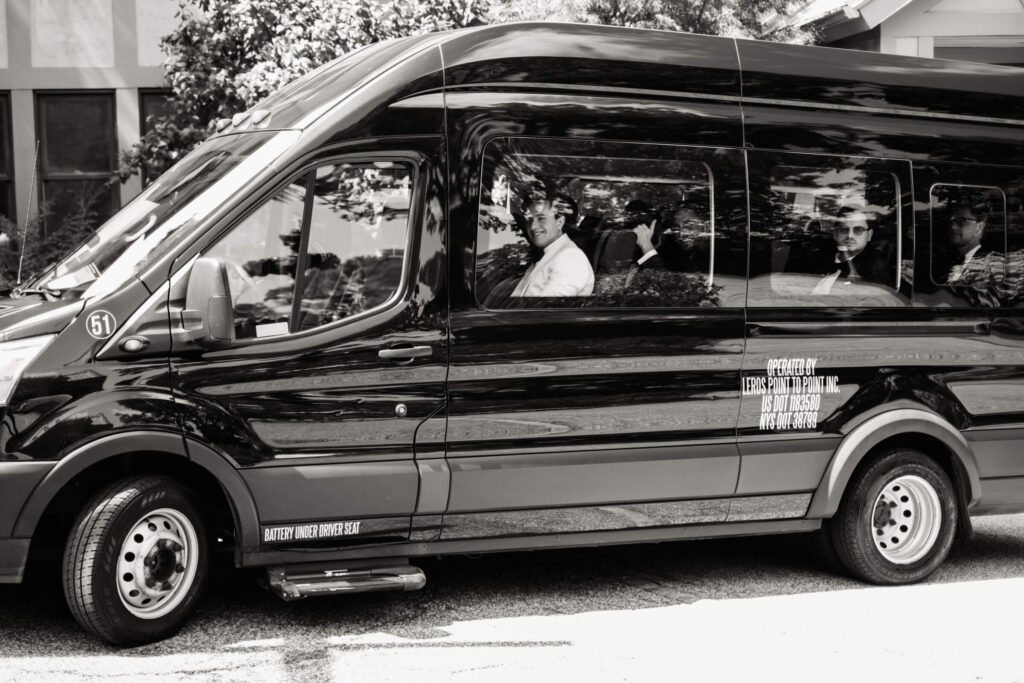 Black and white photo of the groom and groomsmen riding together in a shuttle en route to Bedford Golf & Tennis Club for the ceremony