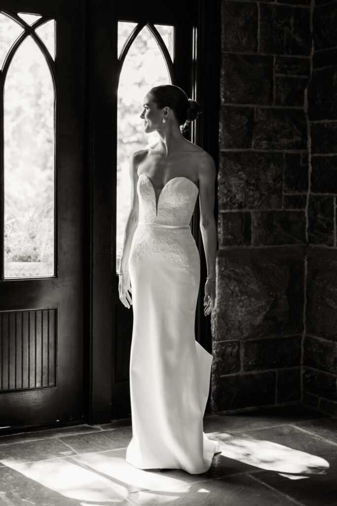 Elegant black and white portrait of the bride standing at the arched doors of the Castle Hotel, bathed in natural light