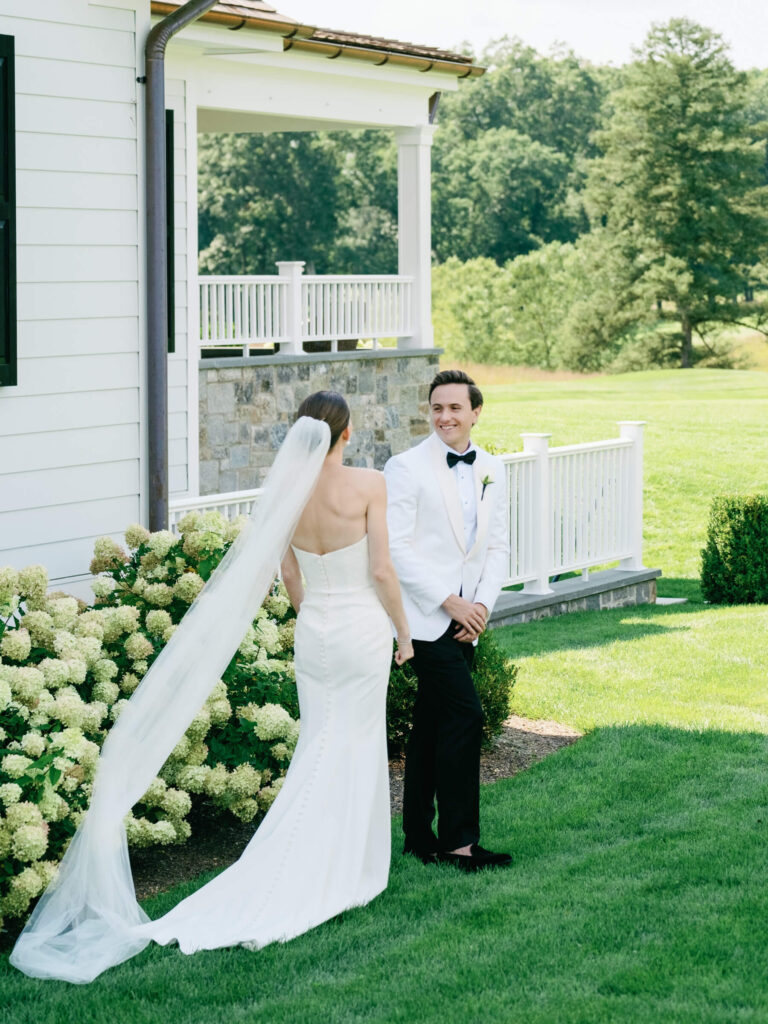 Bride and groom share joyful first look moment in garden outside Bedford Golf & Tennis Club
