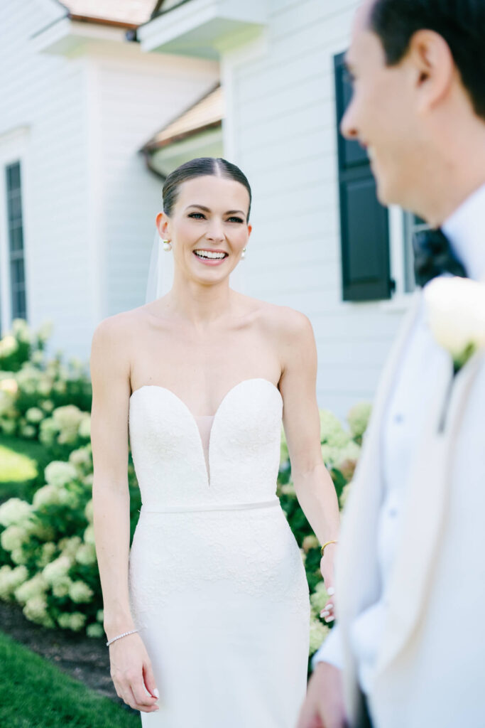 Bride smiles at groom during emotional first look at Bedford Golf & Tennis Club