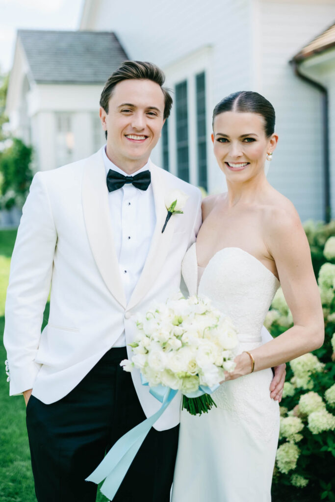 Close-up portrait of bride and groom smiling with bouquet of white roses at New York country club wedding