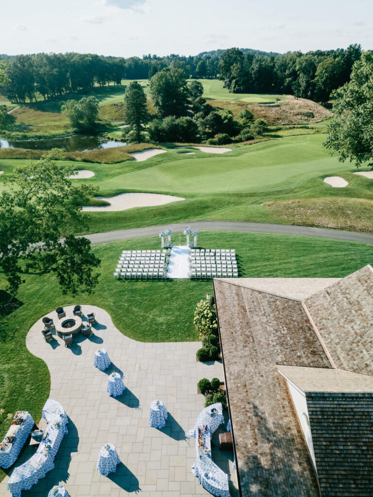 Overhead shot of wedding ceremony and cocktail area, with symmetrical white chairs and elegant bar arrangements