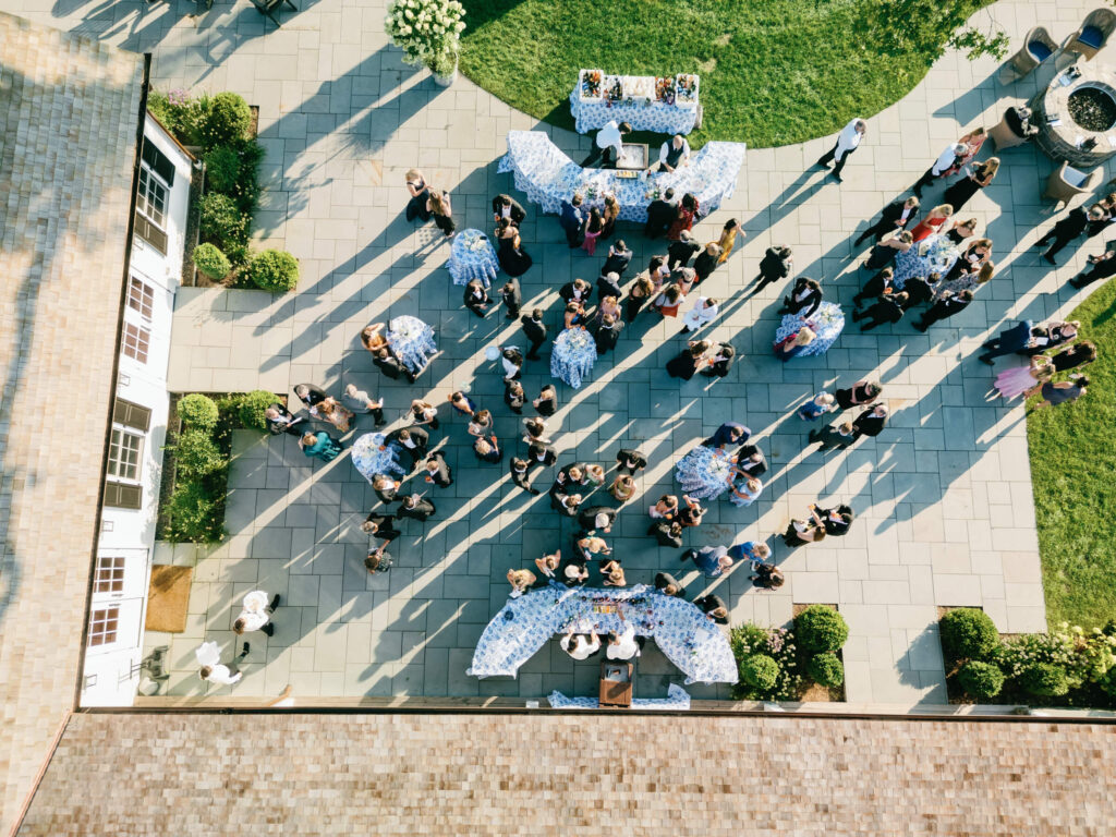 Aerial view of cocktail hour at New York Country Club, with guests mingling around blue and white linen-covered tables