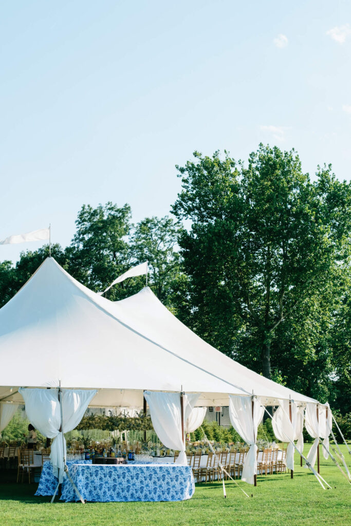Elegant sailcloth tent with draped white fabric and blue floral bar setup on the lawn for a luxury tented reception