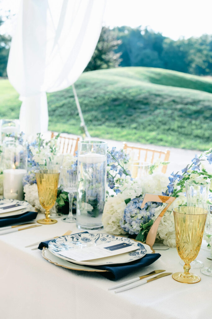 Table number seven surrounded by flickering candles, golden glassware, and overflowing hydrangeas in a dreamy pastel palette.